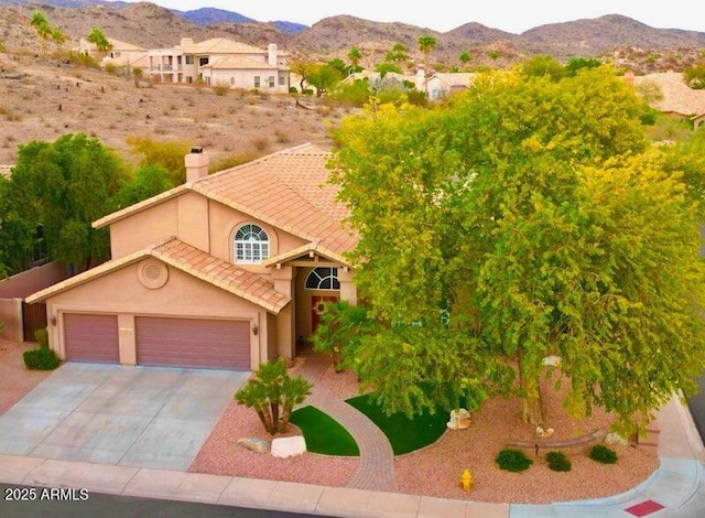 view of front of home with a tile roof, stucco siding, driveway, a garage, and a mountain view