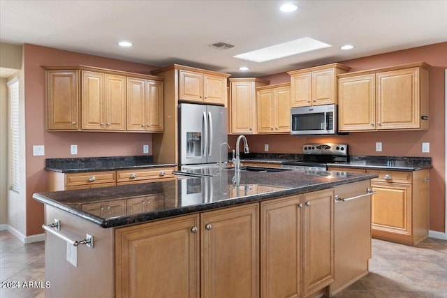 kitchen with recessed lighting, stainless steel appliances, visible vents, dark stone counters, and a center island with sink