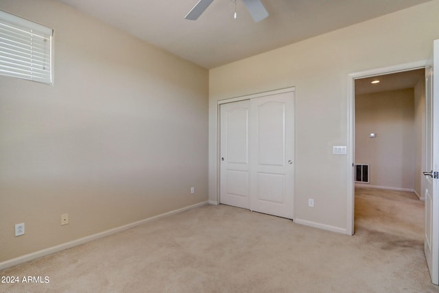 unfurnished bedroom featuring ceiling fan, a closet, and light colored carpet