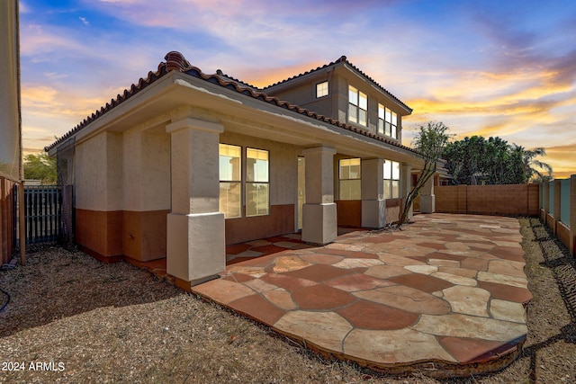 property exterior at dusk featuring a patio area