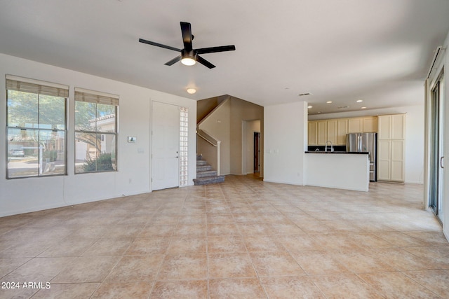 unfurnished living room featuring ceiling fan, sink, and light tile patterned floors