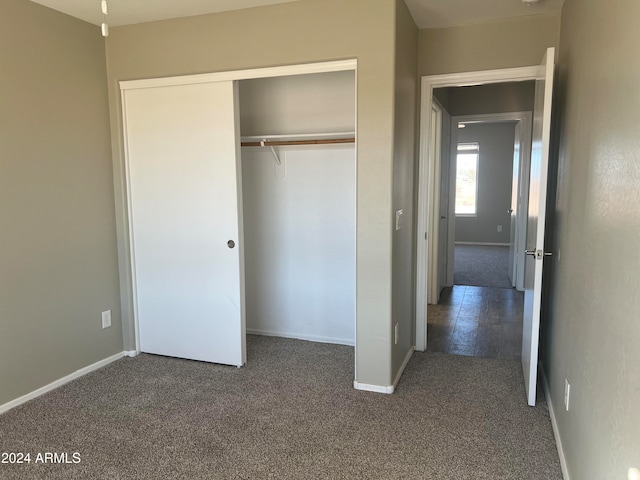 unfurnished bedroom featuring a closet and dark carpet