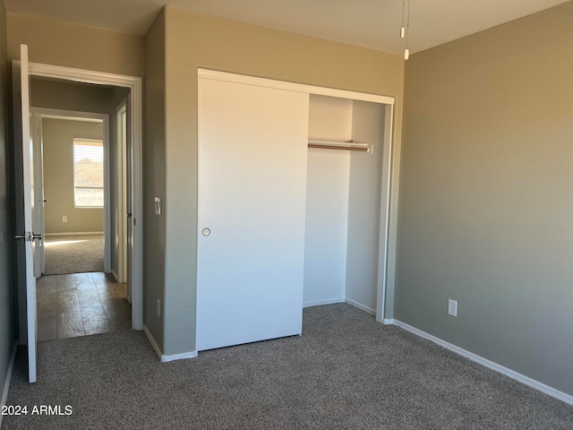 unfurnished bedroom featuring a closet and dark carpet