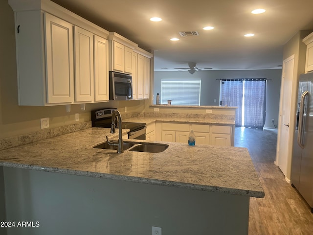 kitchen featuring white cabinetry, appliances with stainless steel finishes, sink, kitchen peninsula, and light hardwood / wood-style flooring