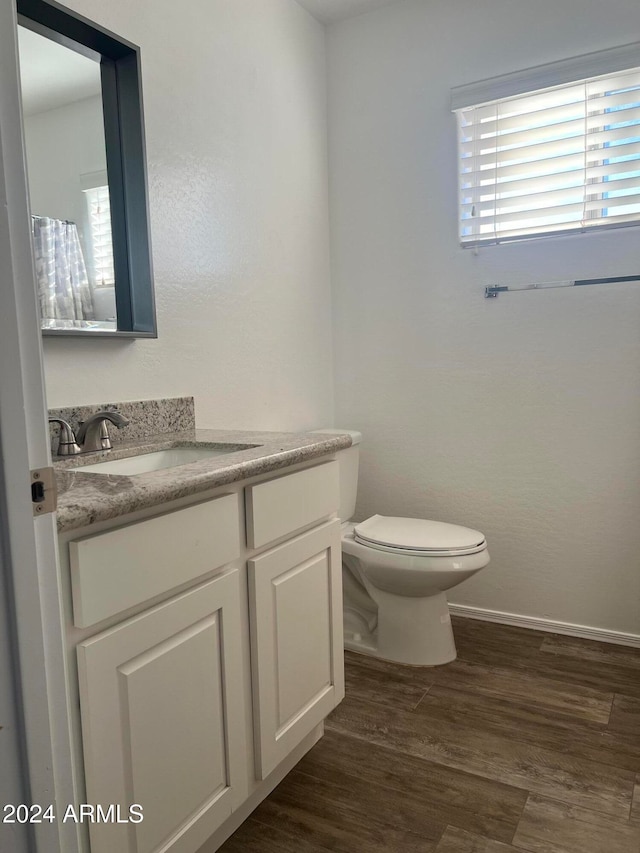 bathroom featuring hardwood / wood-style floors, a wealth of natural light, vanity, and toilet