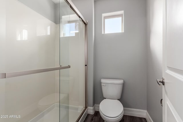 bathroom with hardwood / wood-style flooring, an enclosed shower, and toilet