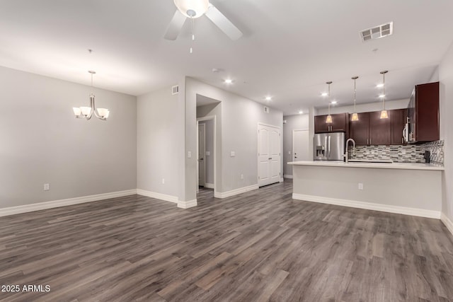 unfurnished living room featuring ceiling fan with notable chandelier and dark hardwood / wood-style flooring