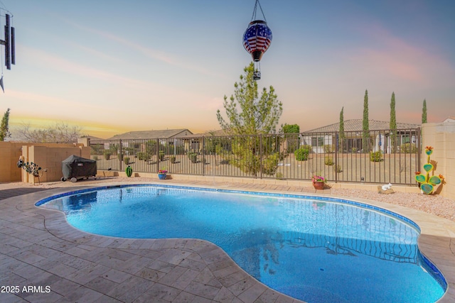 pool at dusk featuring fence, a fenced in pool, and a patio