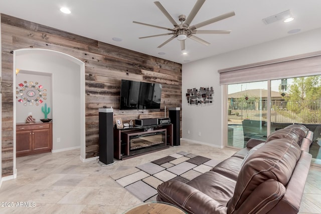 living area with ceiling fan, recessed lighting, an accent wall, wood walls, and baseboards