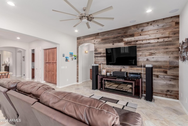 living room with an accent wall, wooden walls, arched walkways, and recessed lighting