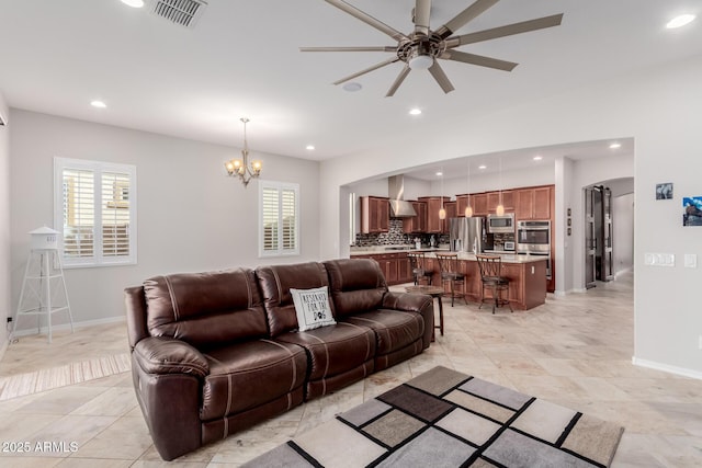 living area with arched walkways, visible vents, baseboards, and recessed lighting