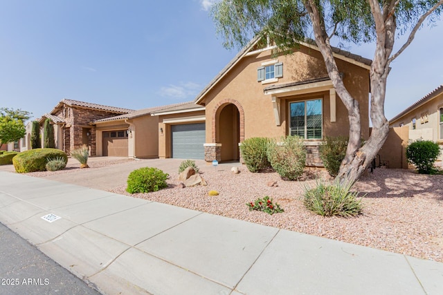 view of front of home featuring a tile roof, stucco siding, an attached garage, stone siding, and driveway