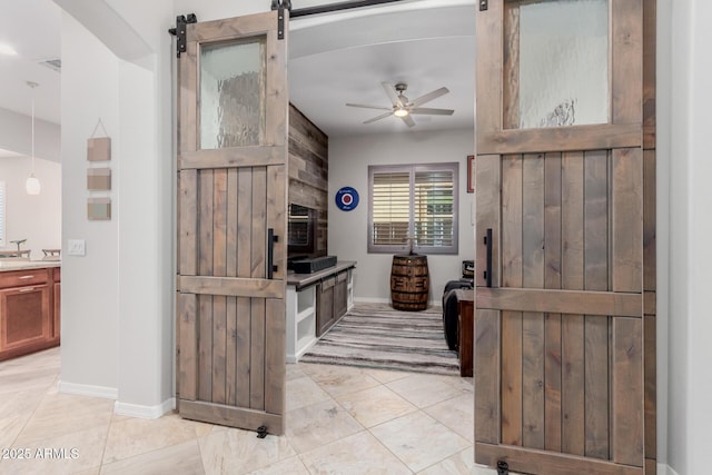 kitchen featuring a ceiling fan, light countertops, light tile patterned floors, and a barn door