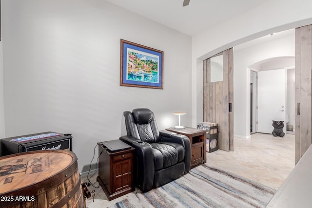 living area with ceiling fan, arched walkways, and baseboards