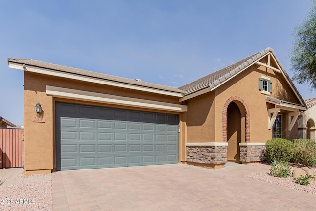 view of front of property with an attached garage, stone siding, decorative driveway, and stucco siding