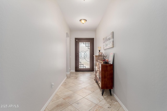 doorway to outside with arched walkways and baseboards