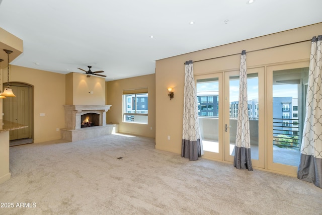 unfurnished living room featuring ceiling fan, light carpet, and a high end fireplace