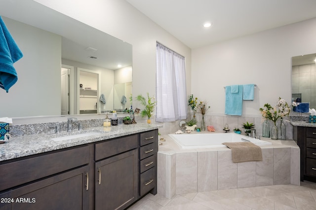 bathroom with vanity, tile patterned floors, and tiled bath