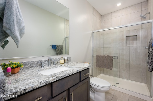 bathroom with toilet, a shower with shower door, vanity, and tile patterned floors