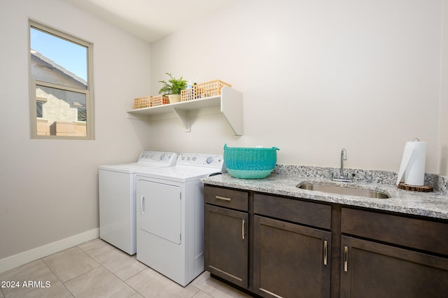 clothes washing area with sink, washing machine and clothes dryer, cabinets, and light tile patterned floors