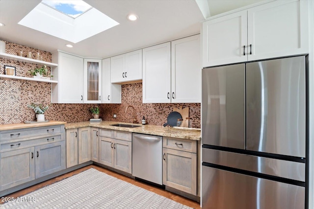 kitchen with appliances with stainless steel finishes, sink, white cabinets, and light stone counters