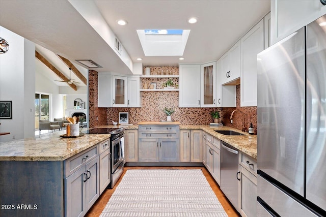 kitchen with sink, stainless steel appliances, white cabinets, and light stone countertops