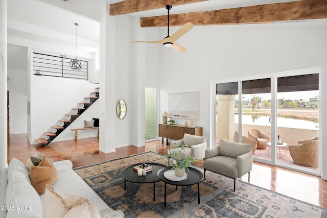 living room featuring beamed ceiling, a high ceiling, and ceiling fan