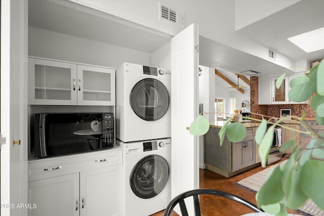 laundry room with stacked washer and dryer and dark hardwood / wood-style floors