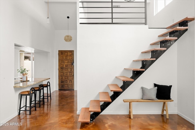 stairway with concrete floors and a high ceiling