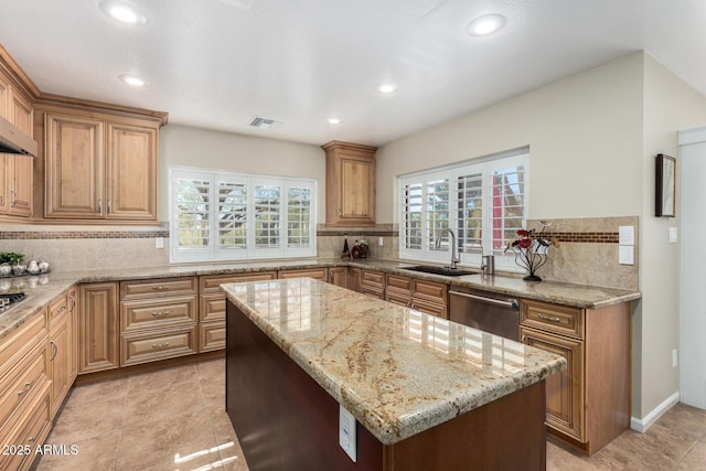 kitchen with sink, backsplash, a center island, light stone counters, and stainless steel dishwasher