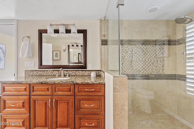 bathroom featuring tasteful backsplash, tiled shower, and vanity