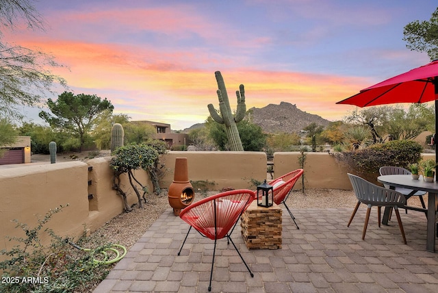 patio terrace at dusk with a mountain view and exterior fireplace