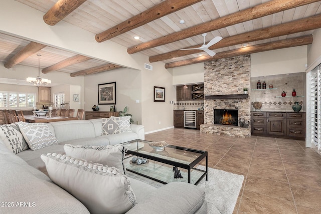 living room featuring wine cooler, beam ceiling, a chandelier, wooden ceiling, and a fireplace