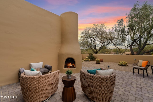 patio terrace at dusk featuring an outdoor fireplace