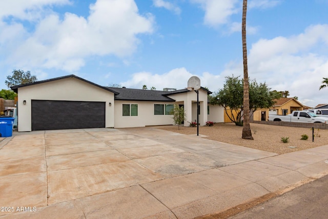 view of front facade with stucco siding, concrete driveway, an attached garage, and fence