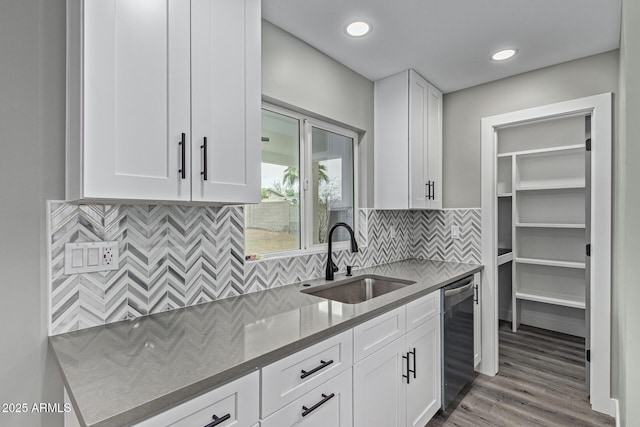 kitchen featuring a sink, decorative backsplash, dishwasher, and white cabinetry