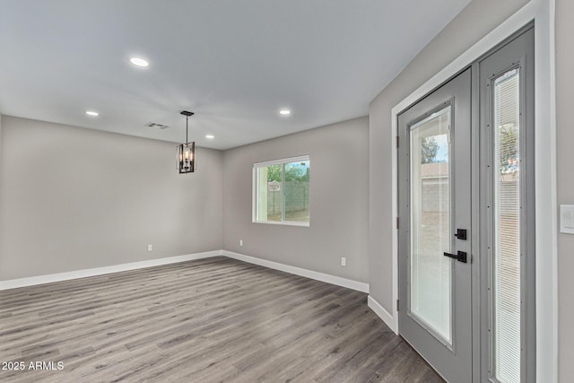 empty room with recessed lighting, wood finished floors, visible vents, and baseboards