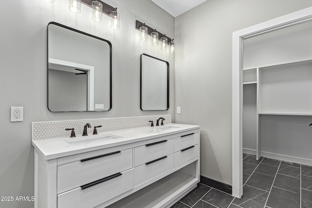 full bath featuring decorative backsplash, double vanity, baseboards, and a sink