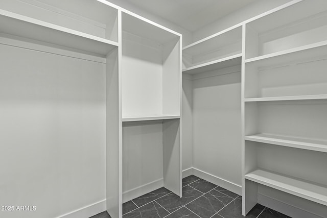 walk in closet featuring marble finish floor