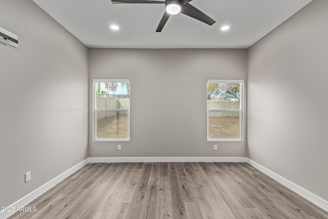 empty room with recessed lighting, wood finished floors, baseboards, and a wealth of natural light