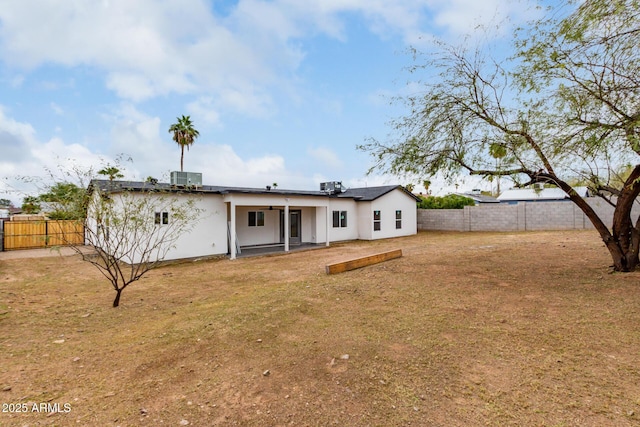 back of house featuring a fenced backyard, stucco siding, central air condition unit, a patio area, and a lawn