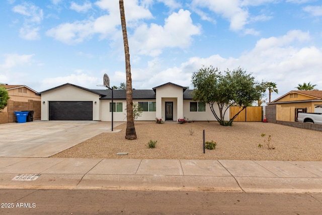 view of front of property featuring stucco siding, an attached garage, concrete driveway, and fence