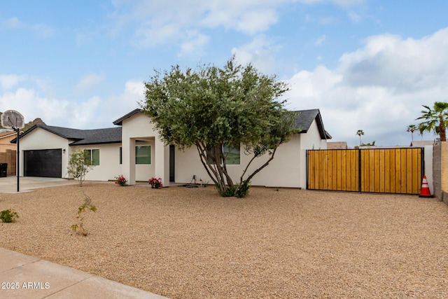 view of front of home featuring stucco siding, driveway, a gate, fence, and an attached garage