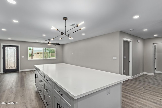 kitchen with wood finished floors, visible vents, recessed lighting, light countertops, and a center island