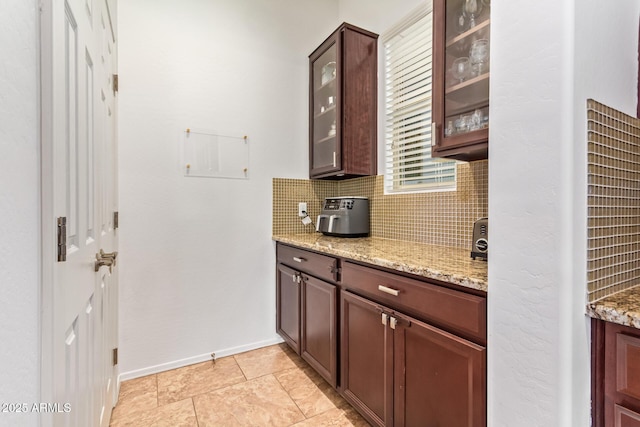 15862 W Fillmore St, Goodyear, AZ 85338 - kitchen with backsplash, glass insert cabinets, light stone countertops, and baseboards