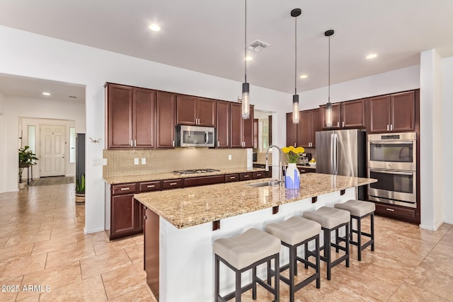 15862 W Fillmore St, Goodyear, AZ 85338 - kitchen with stainless steel appliances, a sink, decorative backsplash, a breakfast bar area, and decorative light fixtures