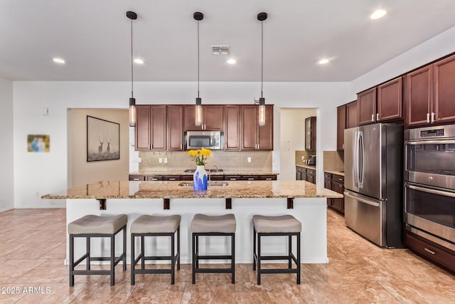 15862 W Fillmore St, Goodyear, AZ 85338 - kitchen featuring stainless steel appliances, a kitchen breakfast bar, tasteful backsplash, a kitchen island with sink, and recessed lighting