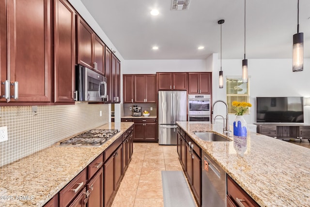 15862 W Fillmore St, Goodyear, AZ 85338 - kitchen with stainless steel appliances, a sink, reddish brown cabinets, hanging light fixtures, and backsplash