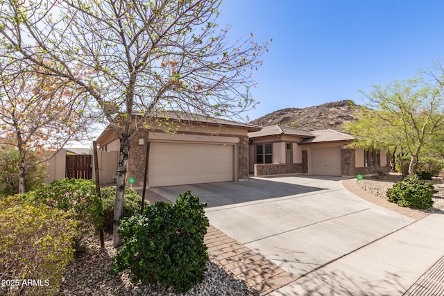 view of front of property with stucco siding, an attached garage, a mountain view, stone siding, and driveway