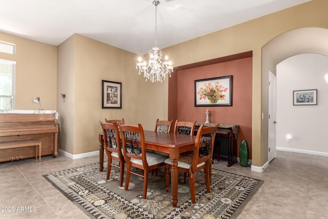 dining room featuring tile patterned flooring, baseboards, arched walkways, and a notable chandelier